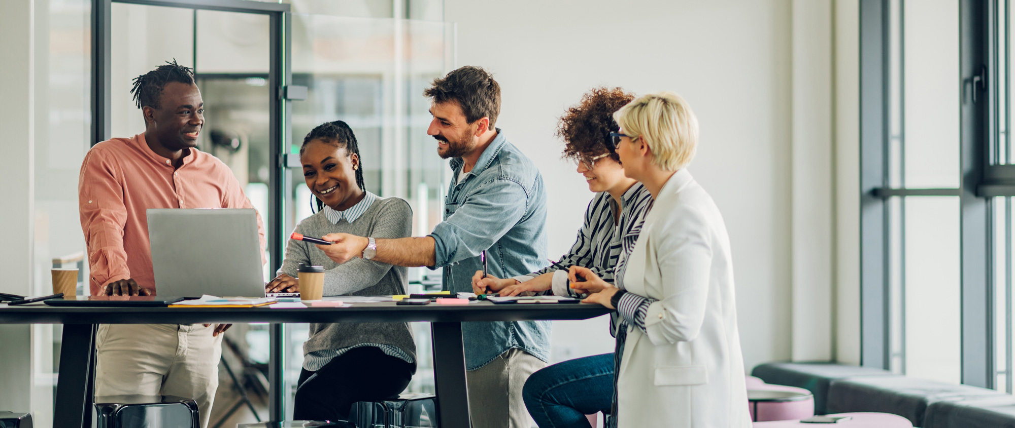 Eine Gruppe diverser Arbeitskolleg:innen arbeiten zusammen an einem Projekt